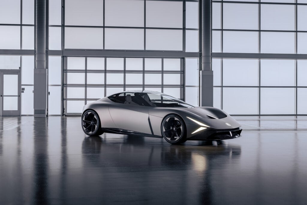 Sleek silver sports car in a bright, glass-walled showroom with polished floor reflections.