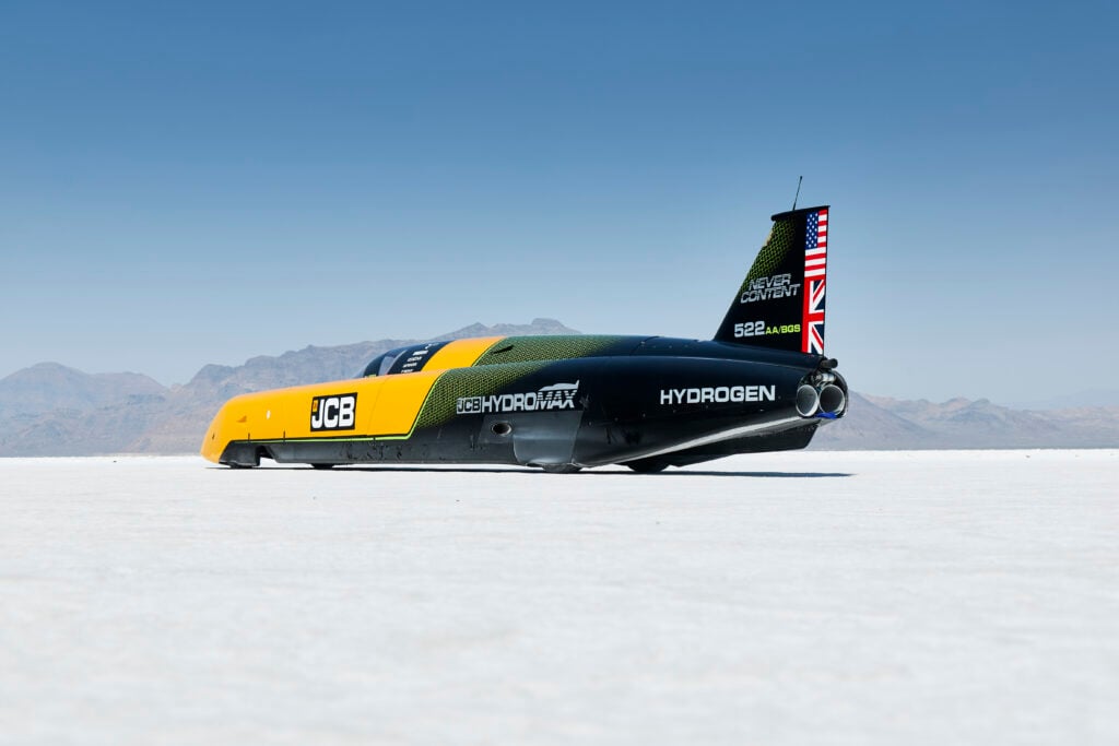 Hydrogen-powered race jet car on a salt flat, tail fin shows Union Jack and U.S. flag with branding.
