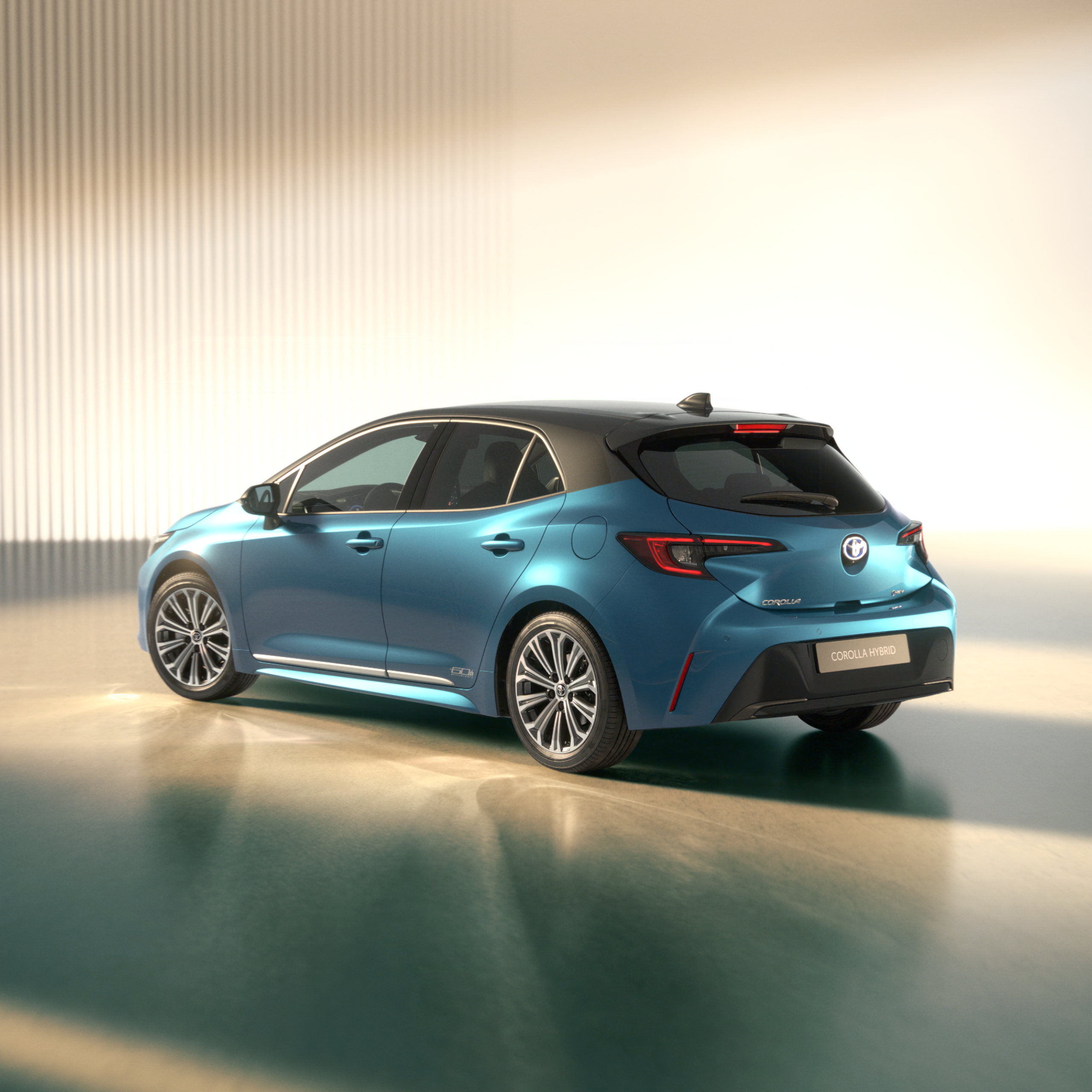 Rear three-quarter view of a blue Toyota Corolla Hybrid in a bright showroom.