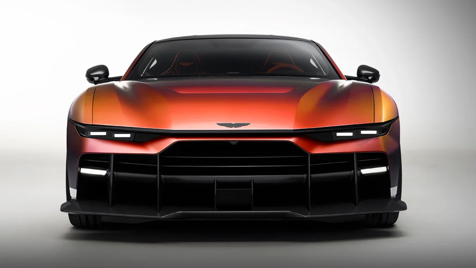 Front view of an orange sports car with a black grille, LED headlights, and carbon-fiber aero details.