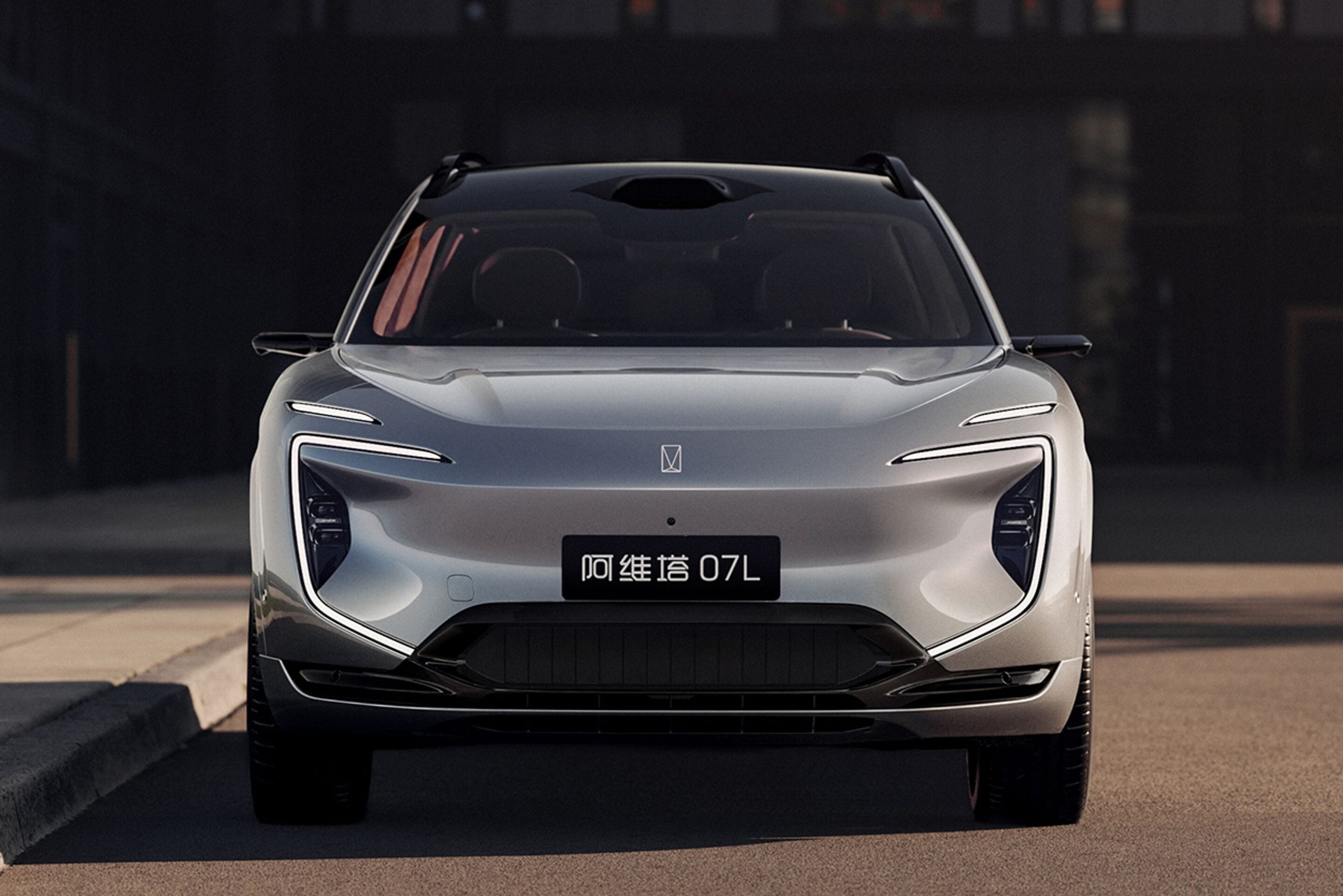 Front view of a silver futuristic SUV facing the camera, showing the grille-less front and sleek headlights, with a black license plate area containing Chinese characters and '07L'