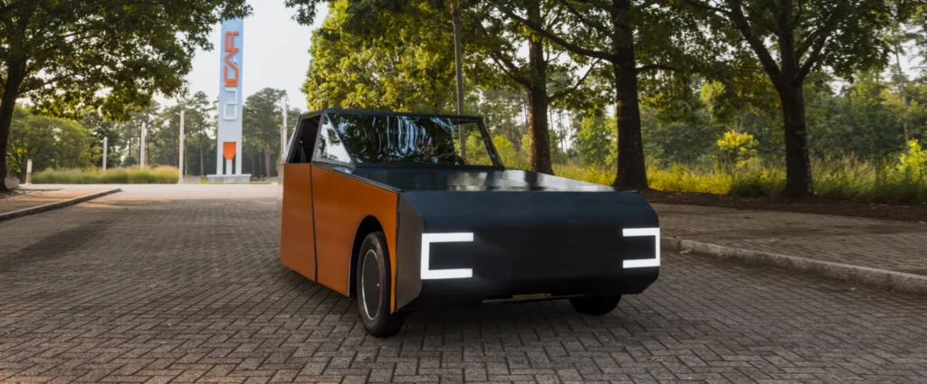 Futuristic black-and-wood panel car parked on a brick street with a tall orange-and-blue sign in the background.