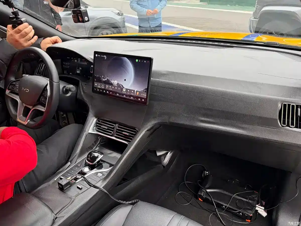 Interior of a car with a large touchscreen tablet mounted on the dashboard, center console controls visible, and loose cables on the passenger side floor.