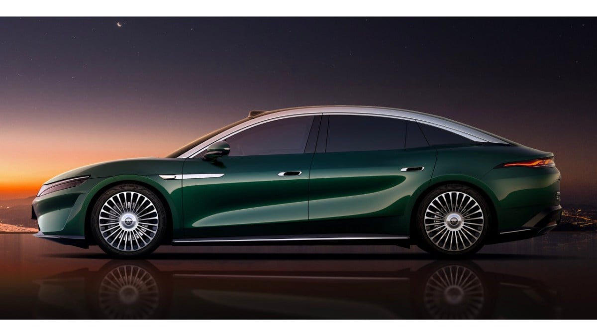 Side view of a dark green luxury sedan parked at dusk with a reflective surface and futuristic alloy wheels.