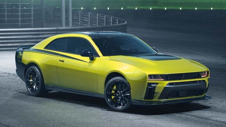 Yellow sports car with black hood and roof parked on a racing track, front three-quarter view with black wheels and accent stripes