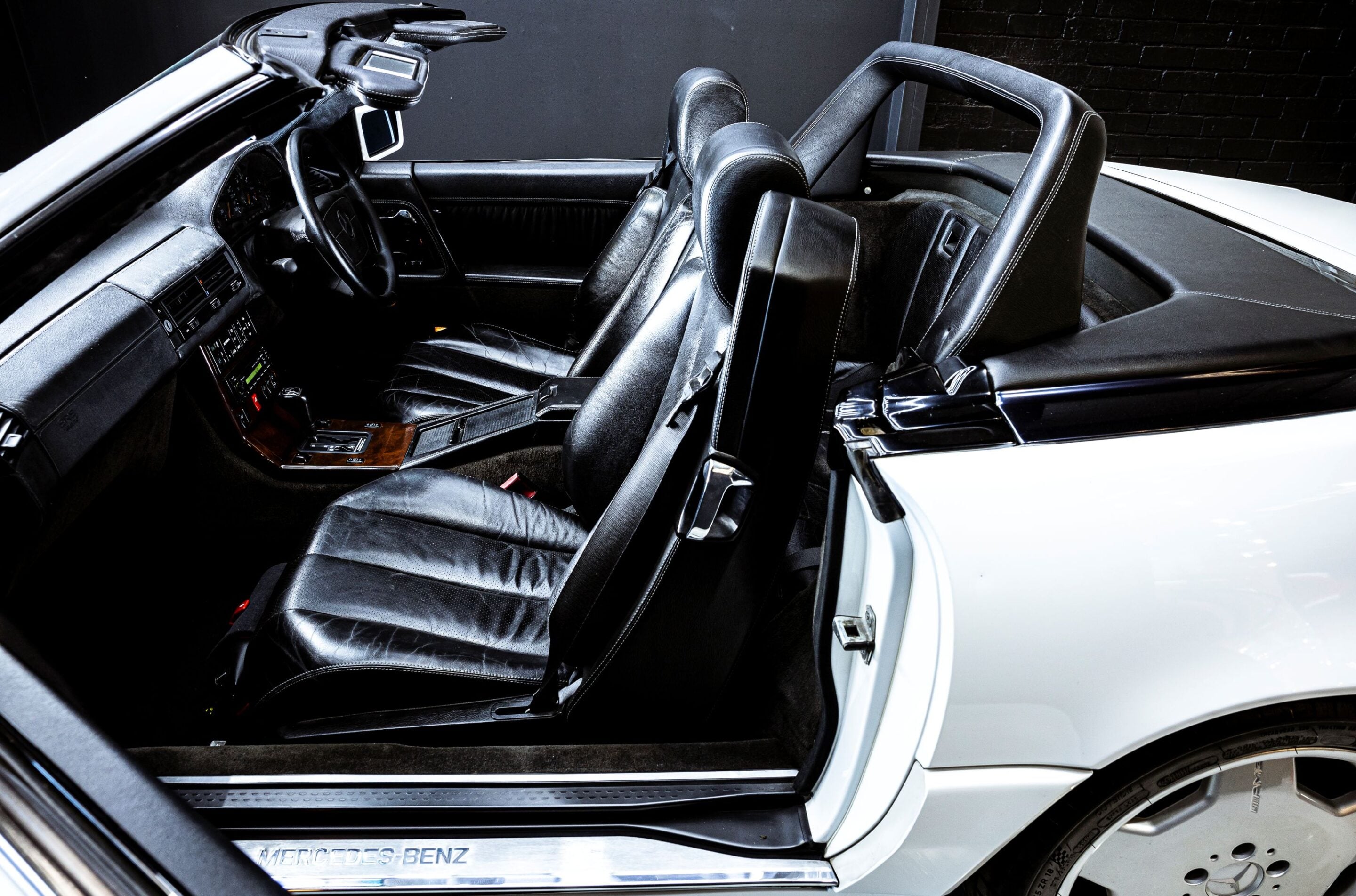Black leather interior of a Mercedes-Benz convertible, showing the front seats, dashboard, and steering wheel.