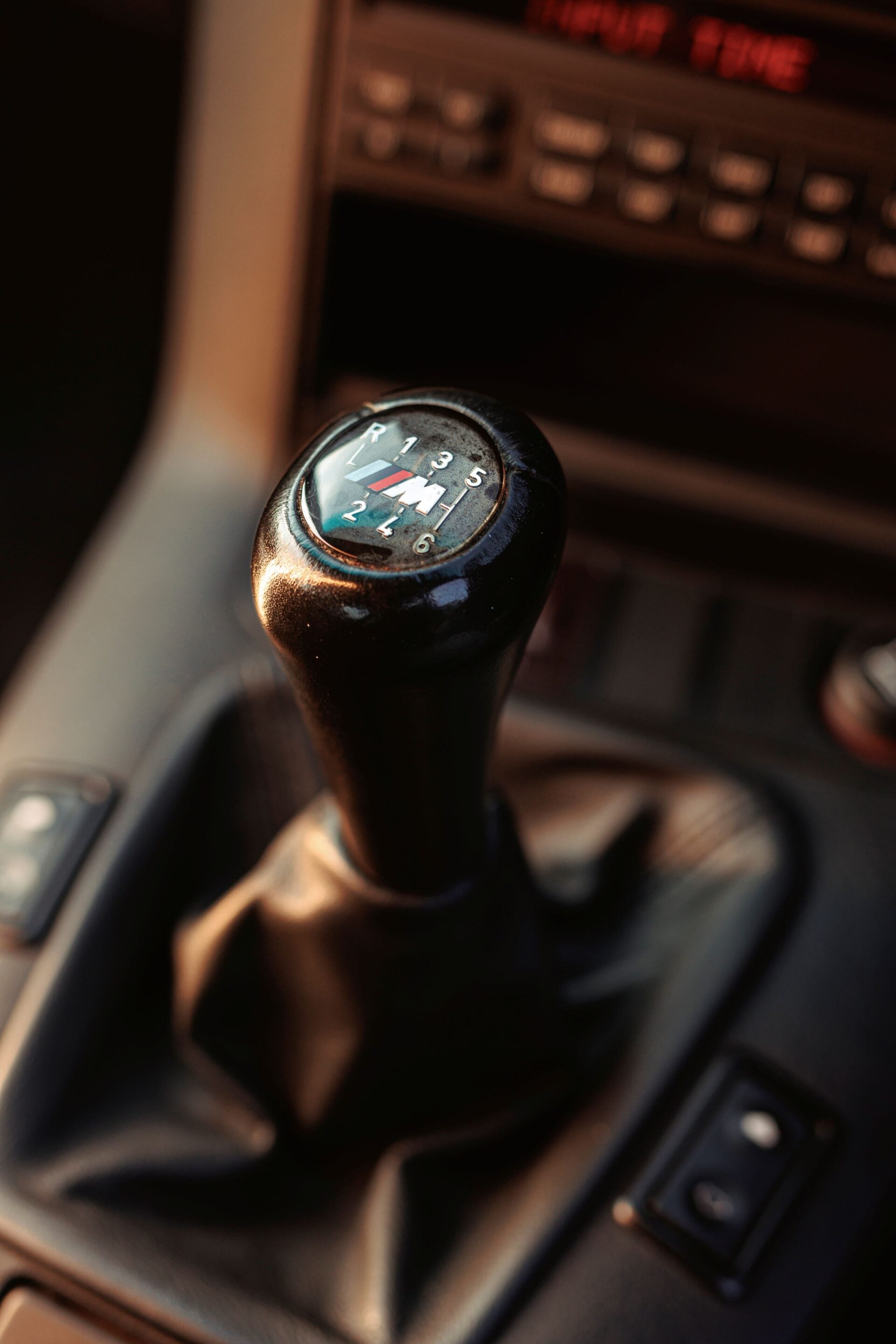 Close-up of a manual gear shift knob showing gears 1–6 and reverse in a car interior.