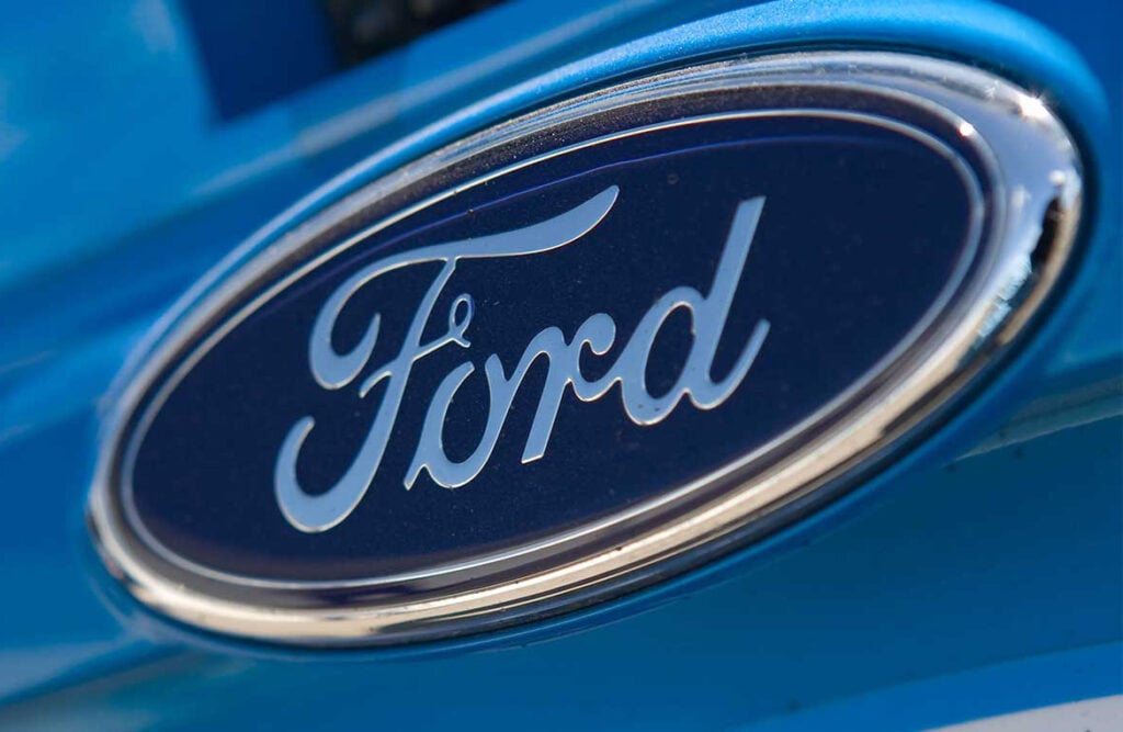 Close-up of a blue Ford car showing the Ford logo in a chrome oval badge on the front grille/hood area