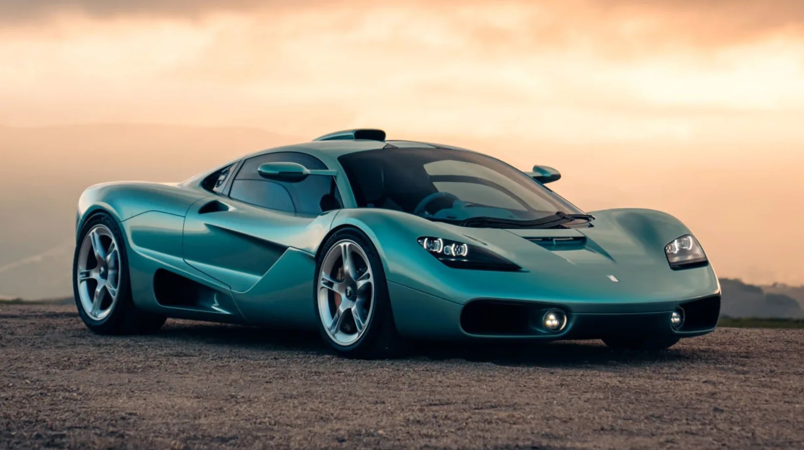 Turquoise sports car parked on a dirt road at sunset with a low, aerodynamic stance