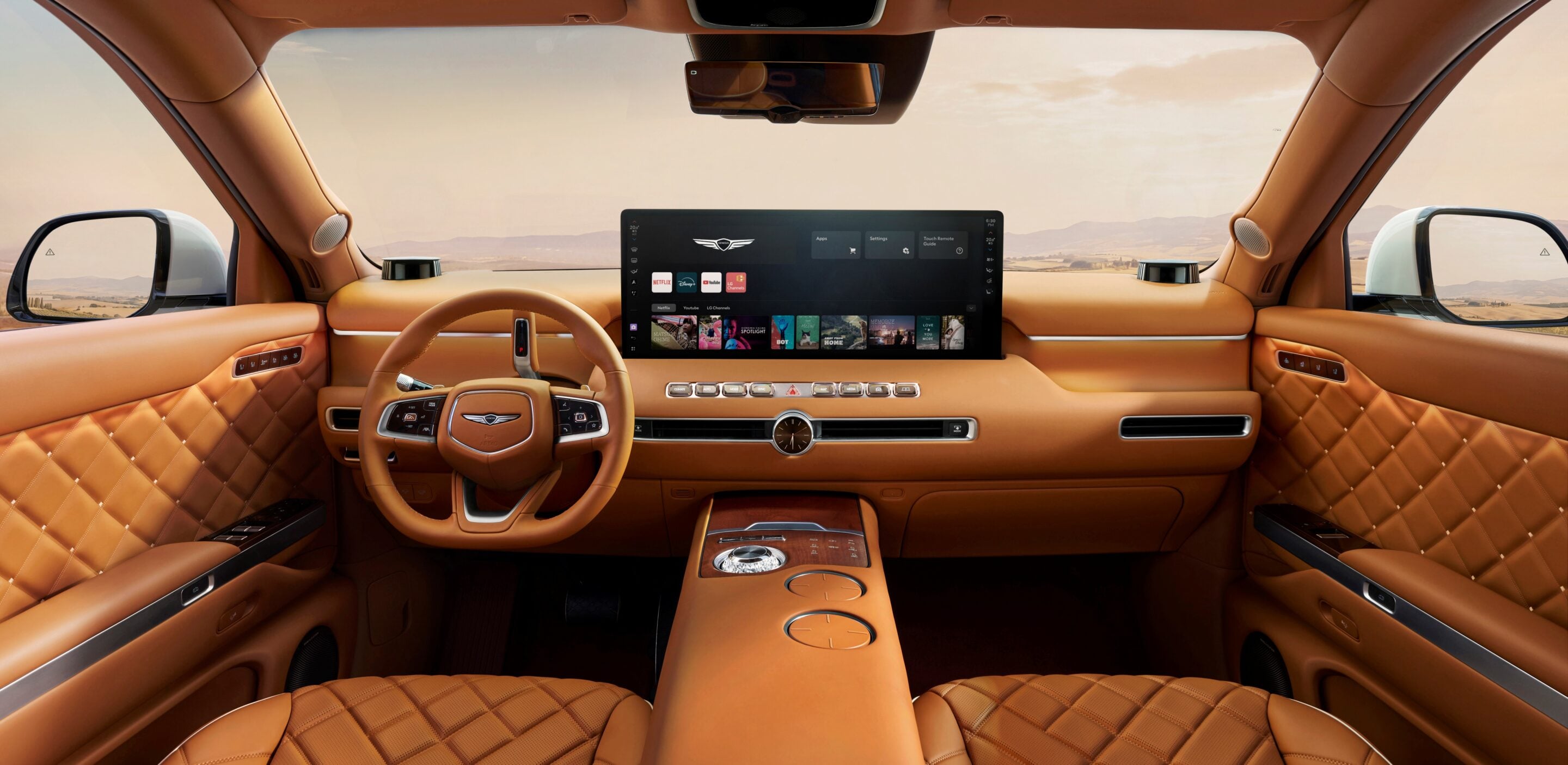 Luxurious tan leather car interior with a wide touchscreen display, steering wheel, and quilted door panels in a desert setting