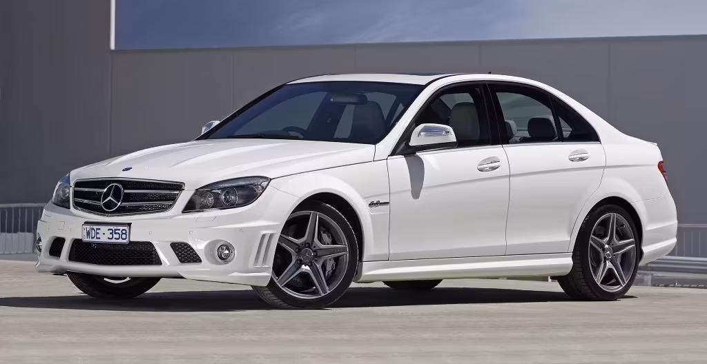 White Mercedes-Benz sedan parked on a rooftop or parking area with a gray building in the background.