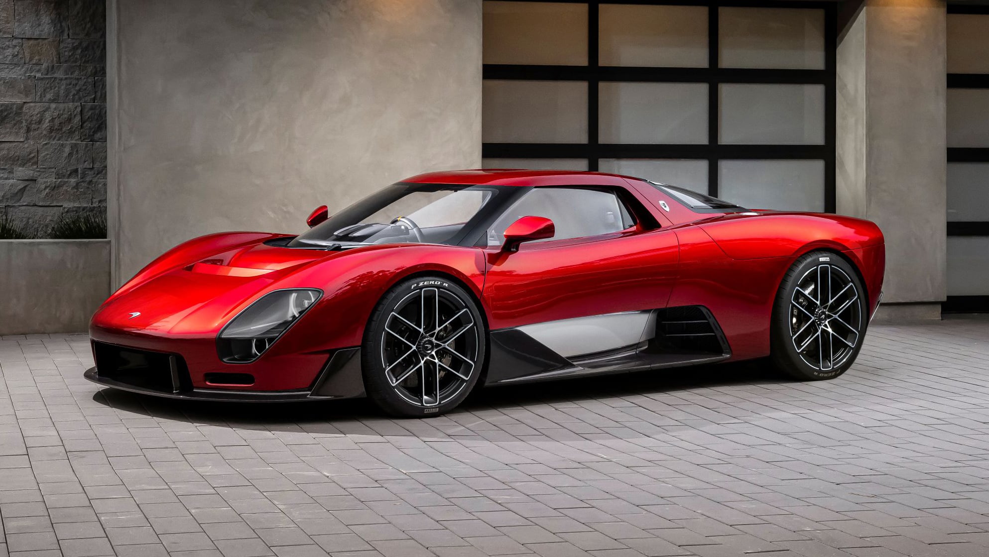 Red Ferrari sports car parked in a modern, tiled showroom with glass panels in the background.