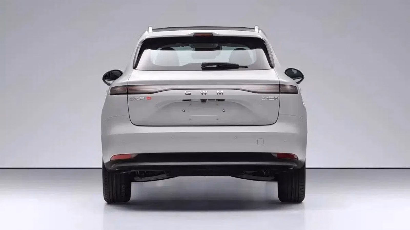 Rear view of a white SUV in a studio setting, showing a full-width tail light bar and the GW M branding on the tailgate.