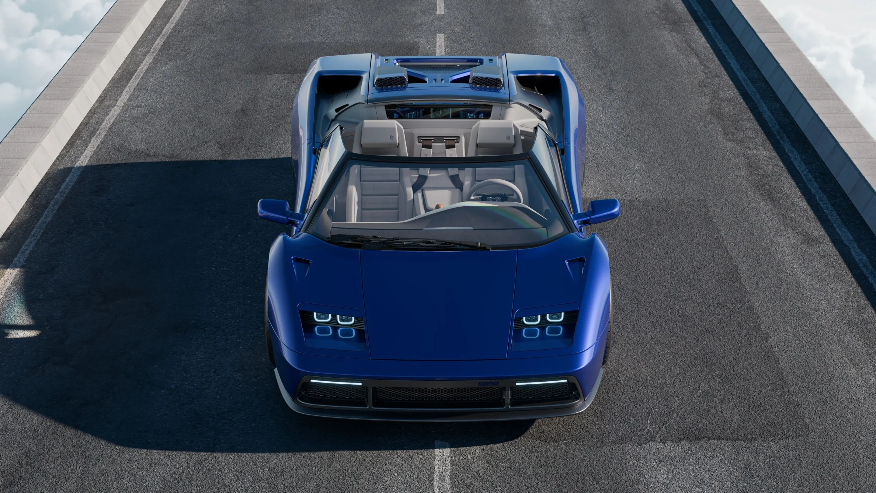 Top-down view of a blue convertible sports car parked/driving on a dark asphalt road with a white center line.