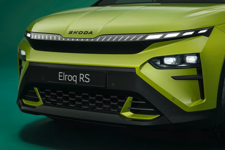 Front close-up of a lime-green Skoda Elroq RS with sleek LED headlights and distinctive front bumper details on a green backdrop.