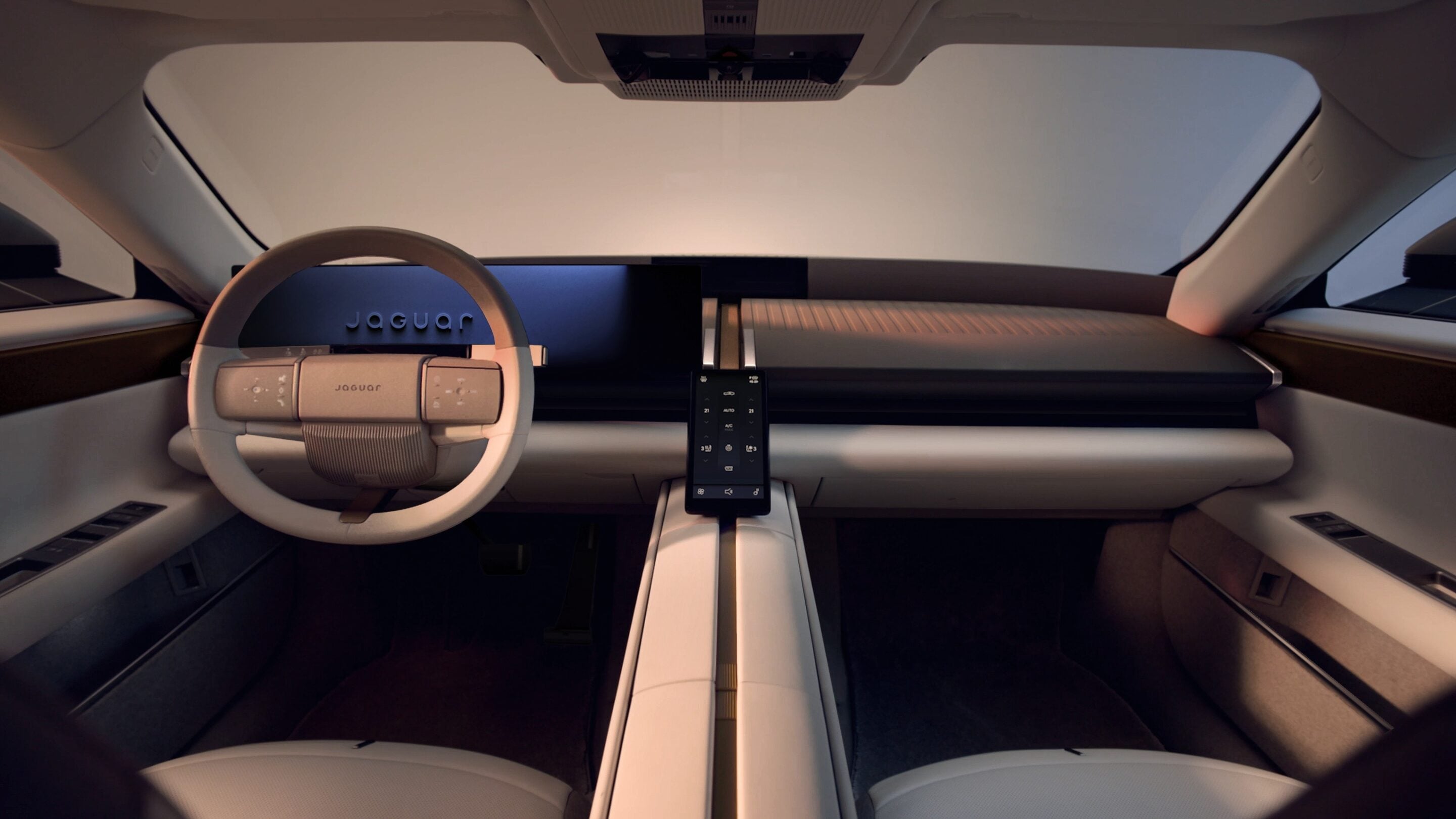 Futuristic Jaguar car cockpit with a circular beige steering wheel and a central touchscreen panel, wide dashboard, and sleek center console.