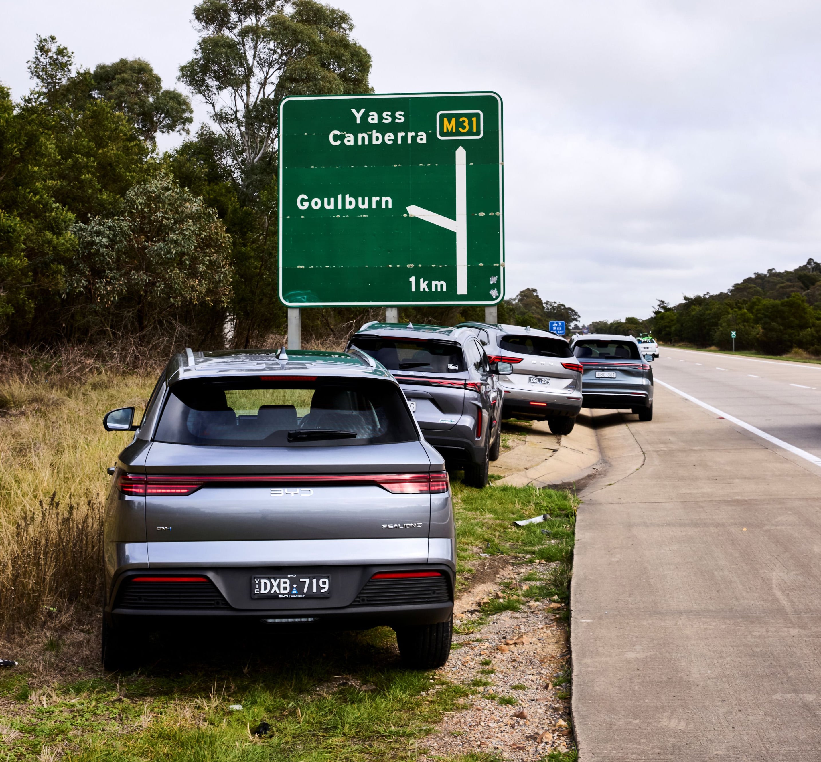 Line of cars bumper to bumper on a highway, with a large green sign showing Yass, Canberra and Goulburn directions (M31) nearby.