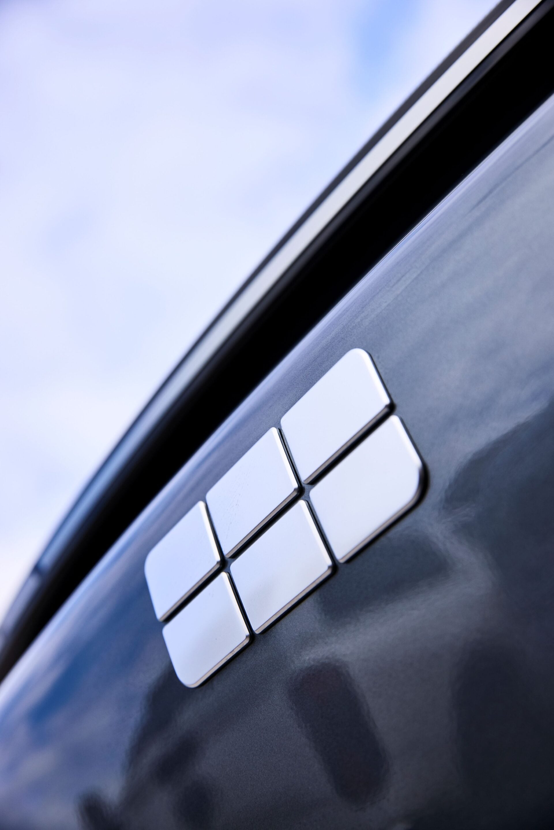 Close-up of white window control buttons on a dark car door panel at an angle.