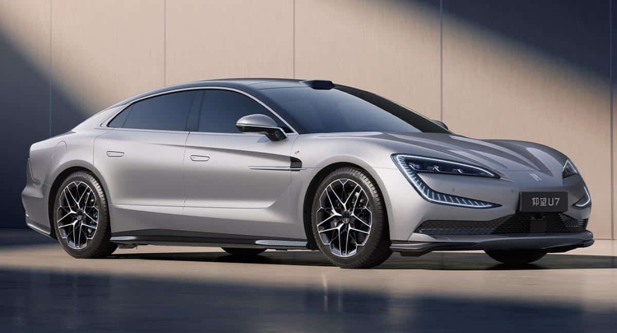 Silver luxury sedan parked outdoors, viewed from the front-right with sleek LED headlights and large multi-spoke wheels.