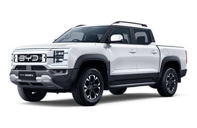 White four-door pickup truck with black trim and roof rails shown on a white studio background.