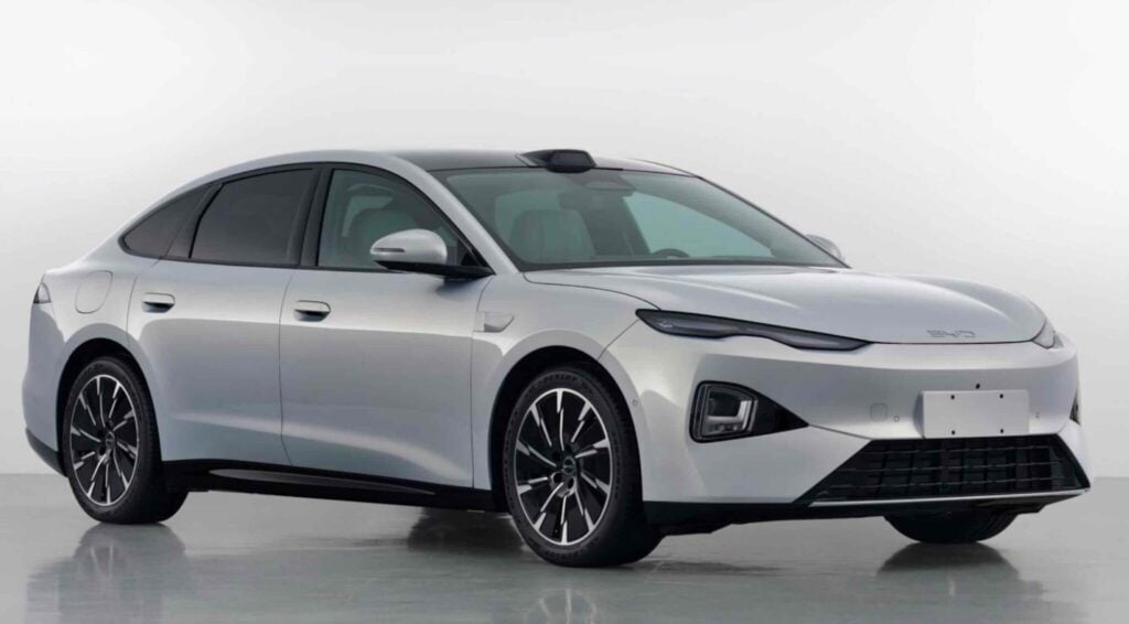 Silver four-door sedan shown from a front-right angle, highlighting its sleek, aerodynamic design, large black alloy wheels, and tinted windows