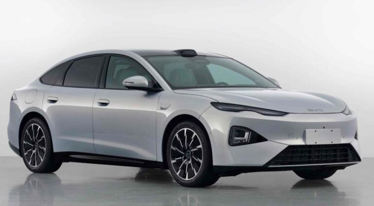 Silver four-door sedan shown from a front-right angle, highlighting its sleek, aerodynamic design, large black alloy wheels, and tinted windows