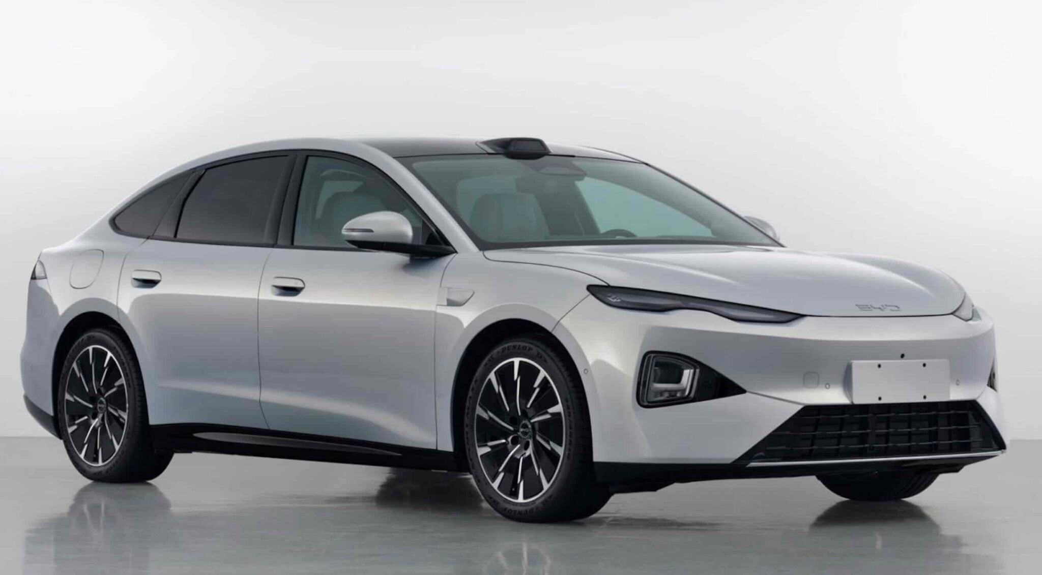 Silver four-door sedan shown from a front-right angle, highlighting its sleek, aerodynamic design, large black alloy wheels, and tinted windows