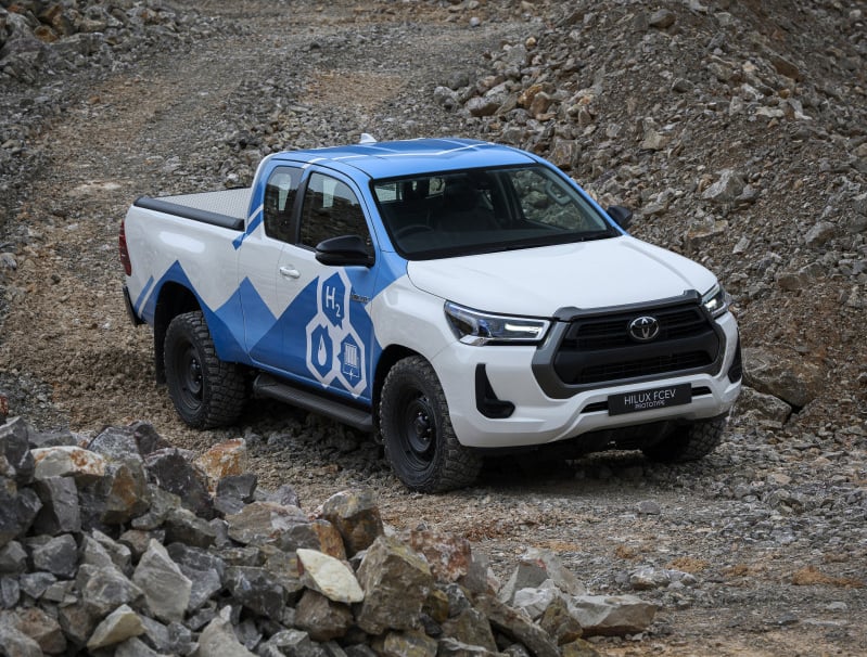 White and blue Toyota Hilux pickup with rescue graphics parked on a rocky quarry slope.