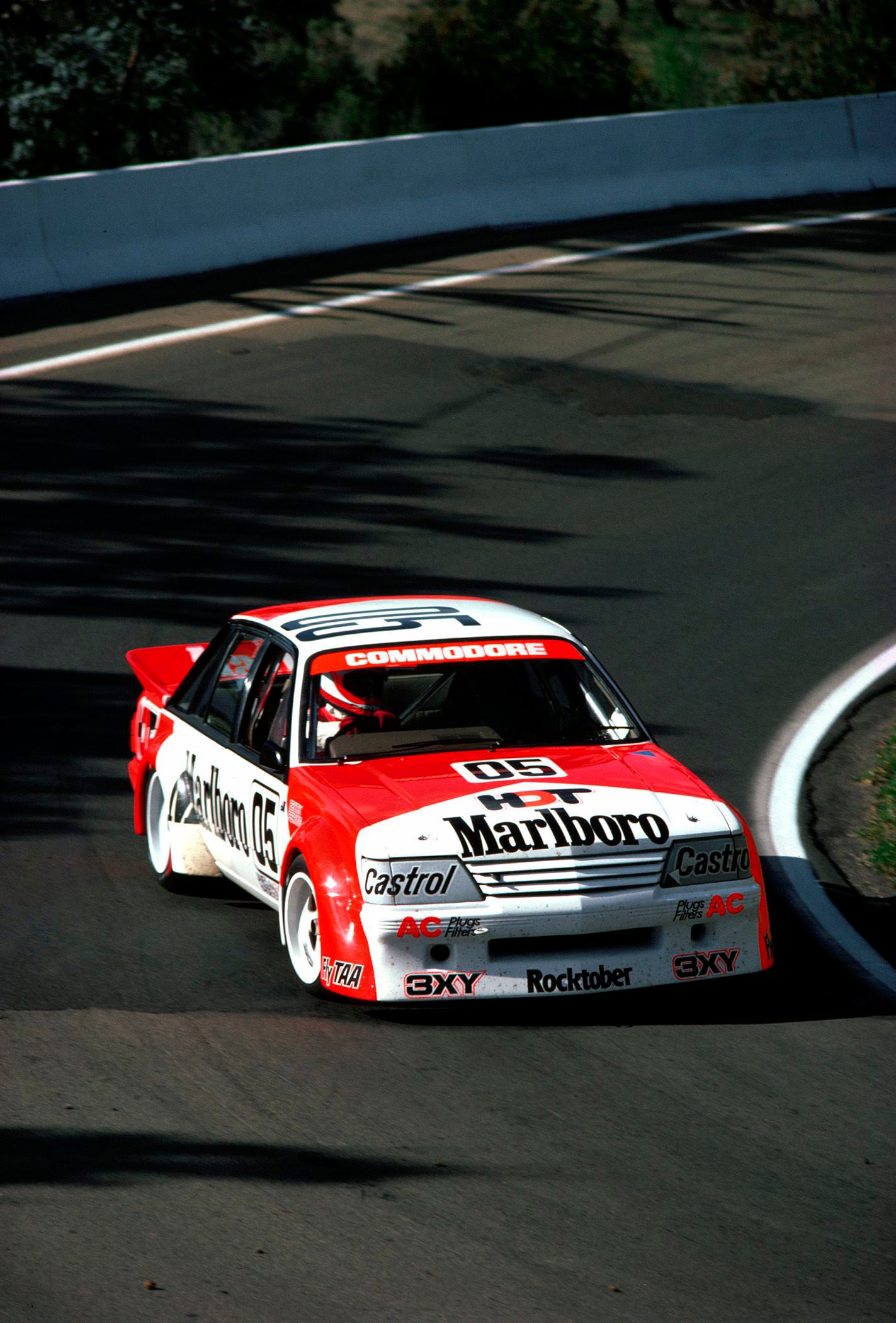 Red and white race car number 05 with Marlboro branding speeding through a curve on a race track, sponsor logos visible on the body.