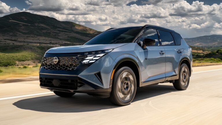 Blue Nissan SUV driving on a highway with hills and cloudy sky in the background.
