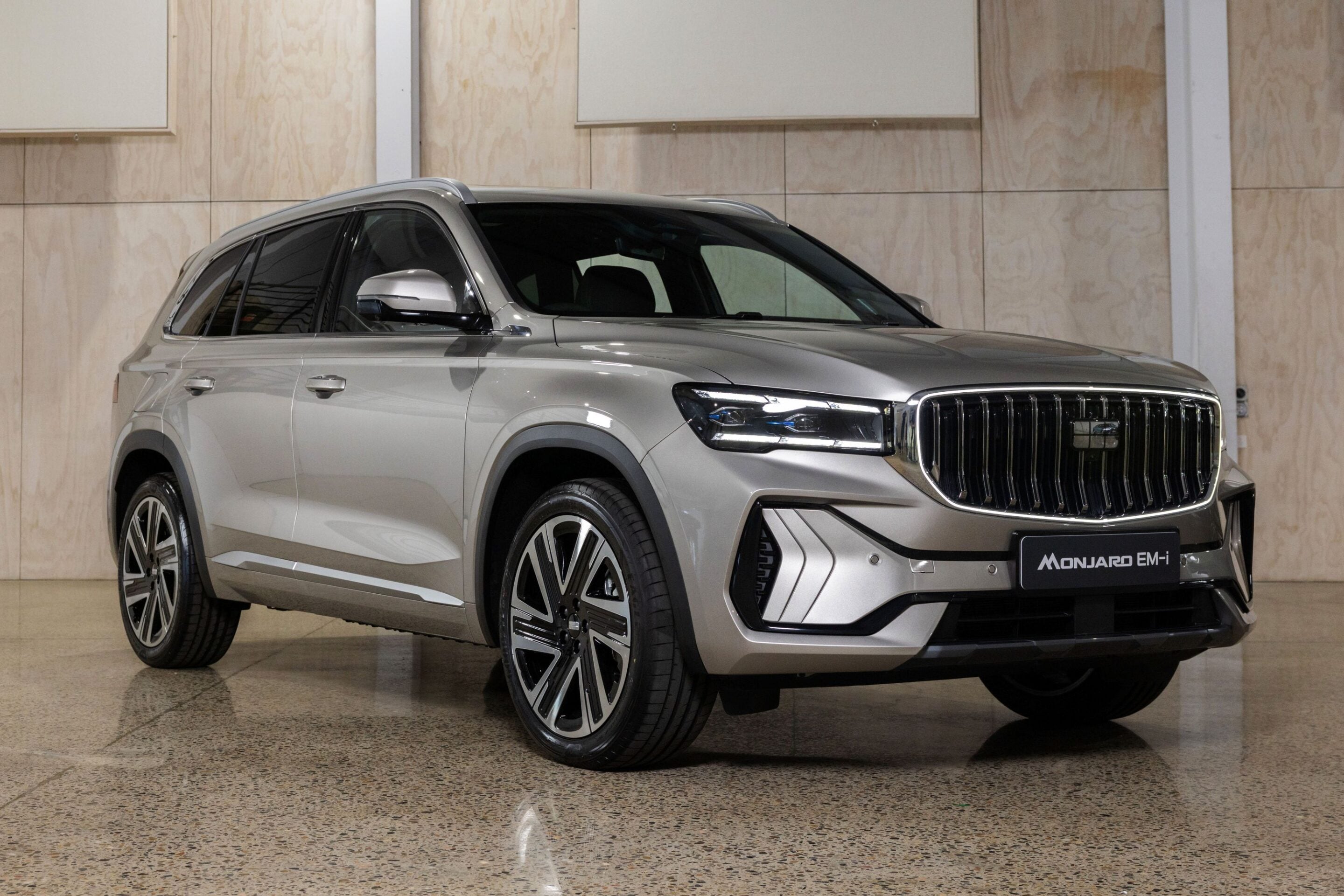 Silver SUV shown in a showroom, front three-quarter view highlighting chrome grille and large wheels.