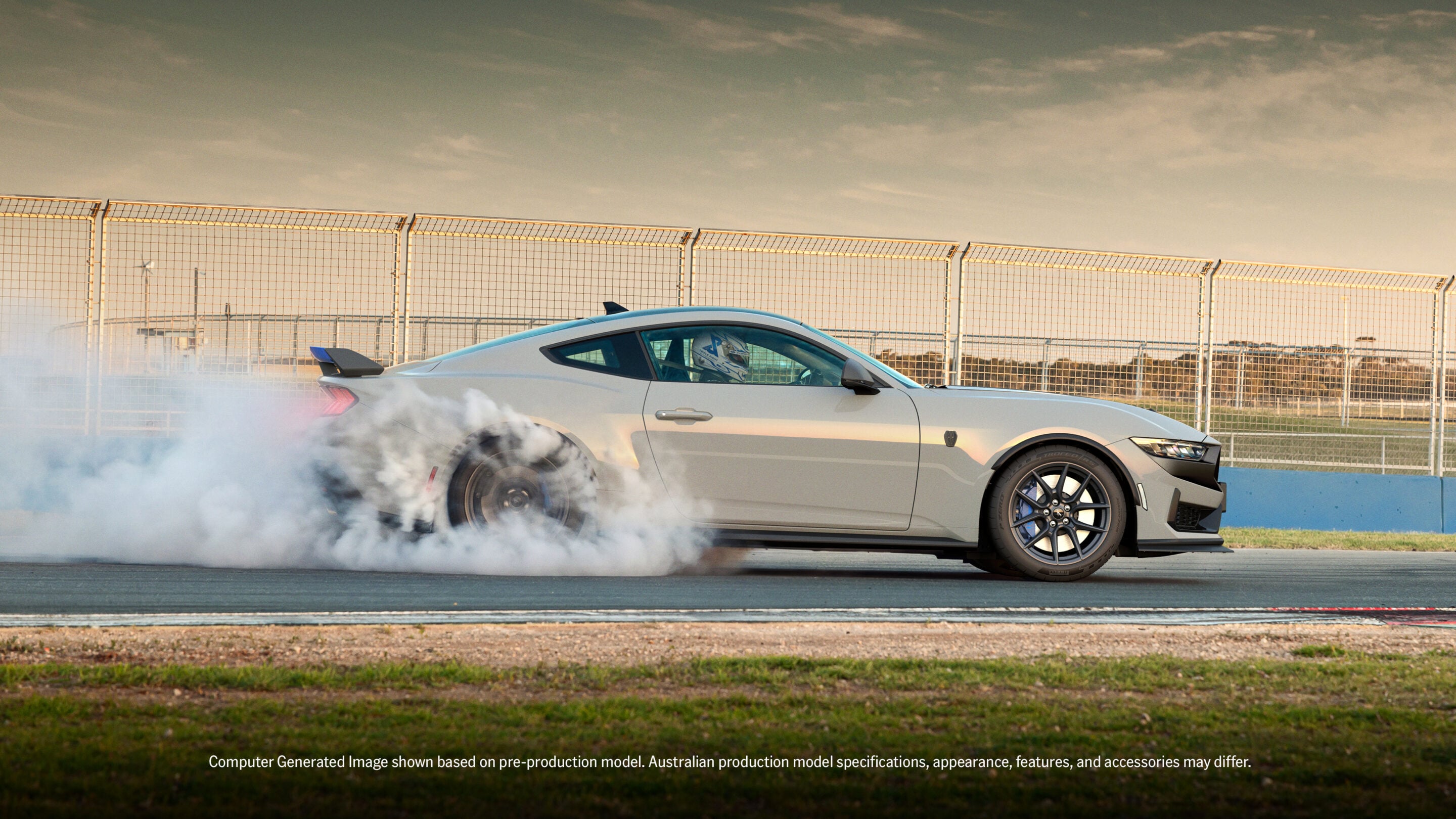 White sports car on a race track, tires smoking as it performs a burnout, chain-link fence in the background.