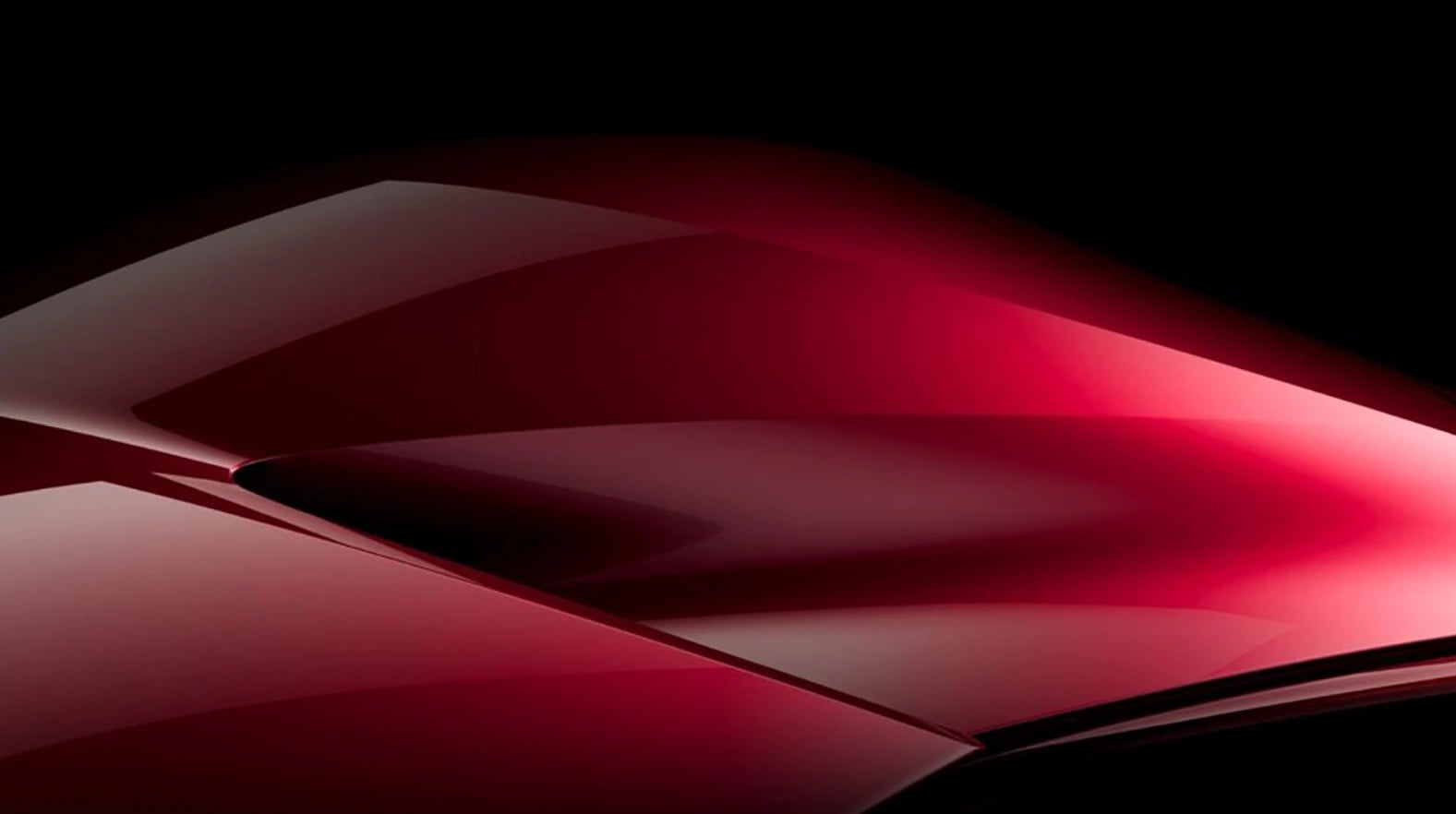 Close-up of glossy red curved panels on a black background, resembling car bodywork.