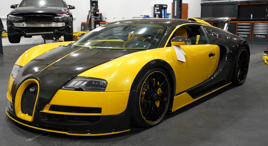 Yellow Bugatti Veyron with black carbon fiber roof in a garage showroom