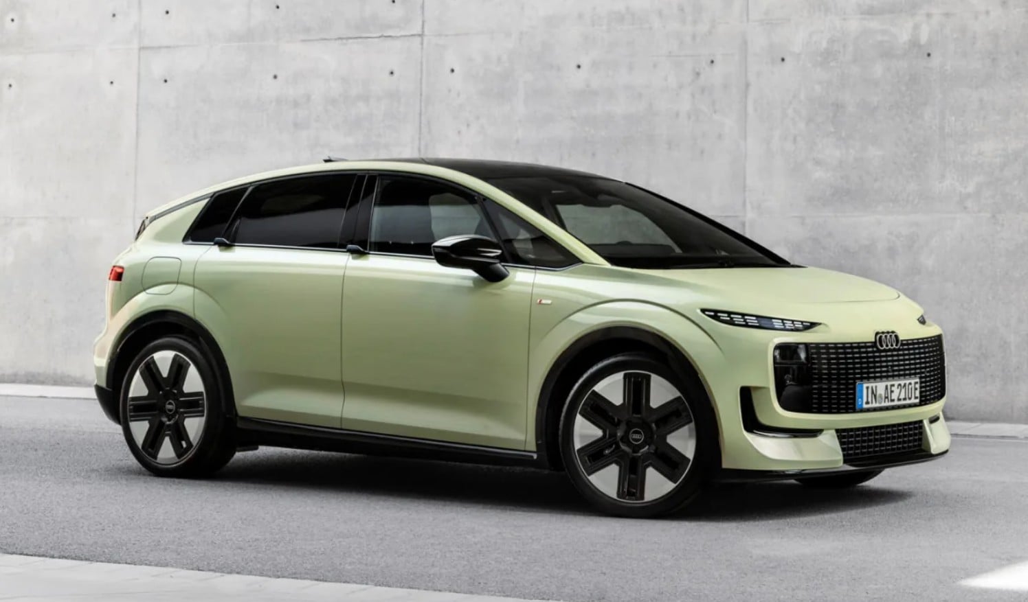 Light green Audi SUV in a three-quarter front view parked beside a concrete wall.