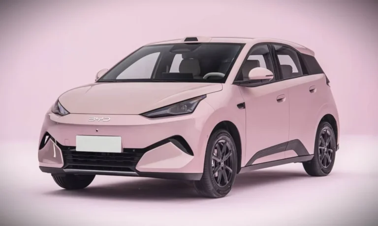 Pink BYD compact hatchback photographed in a studio, three-quarter front view with soft pink background.