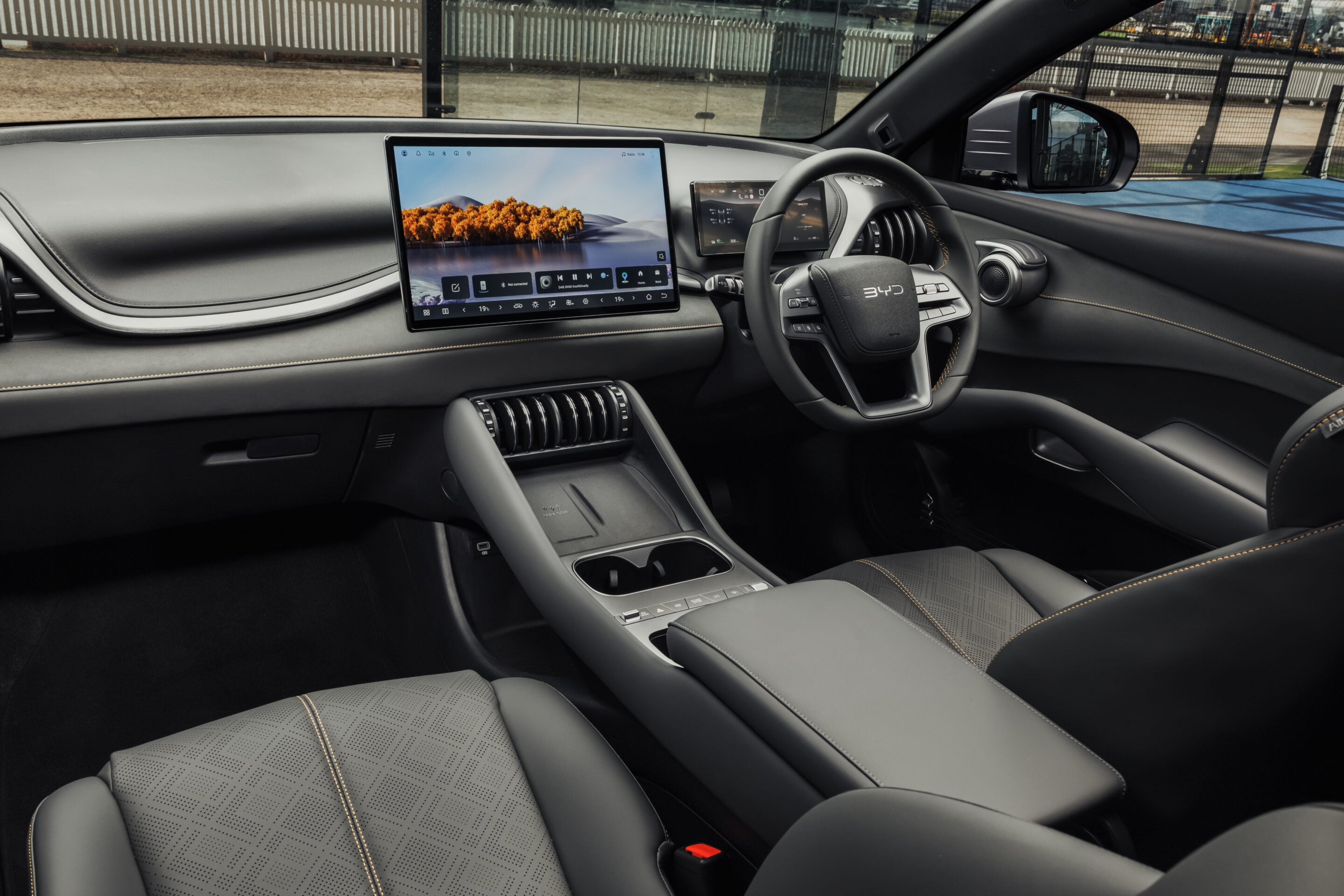 Luxurious car interior with a wide touchscreen infotainment display, stitched leather seats, and a modern steering wheel.