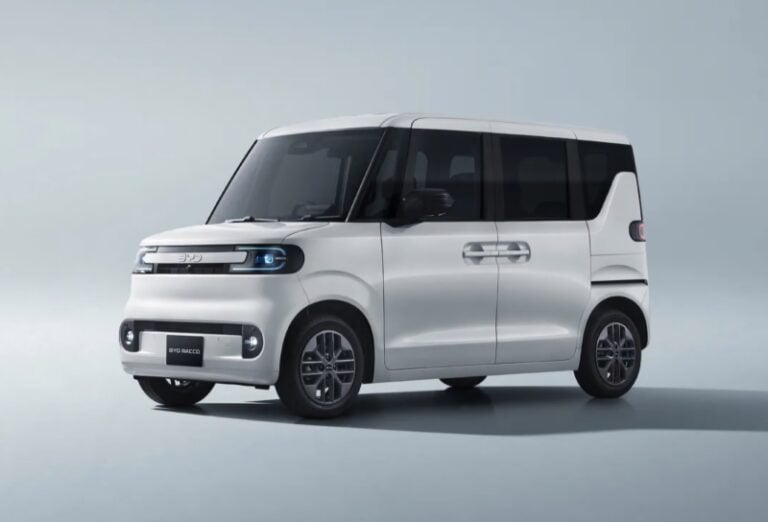 White compact minivan with black-tinted windows in a studio setting, showing sliding doors and a rounded front end.