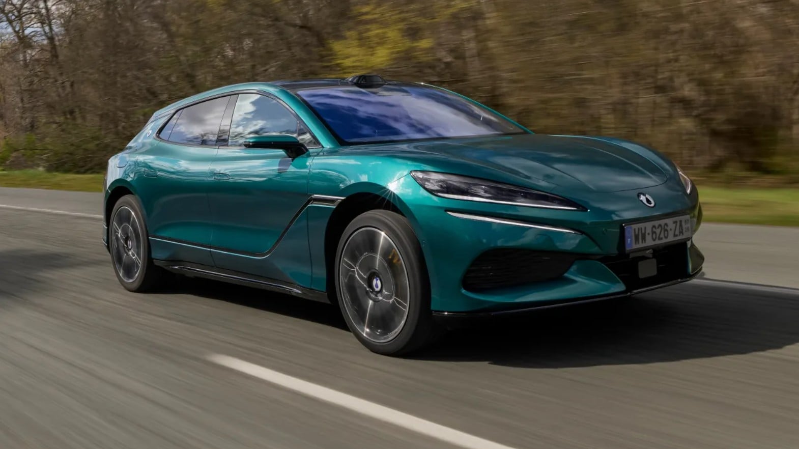 Green-blue BMW i8 sports car driving on a highway, speed blur in background