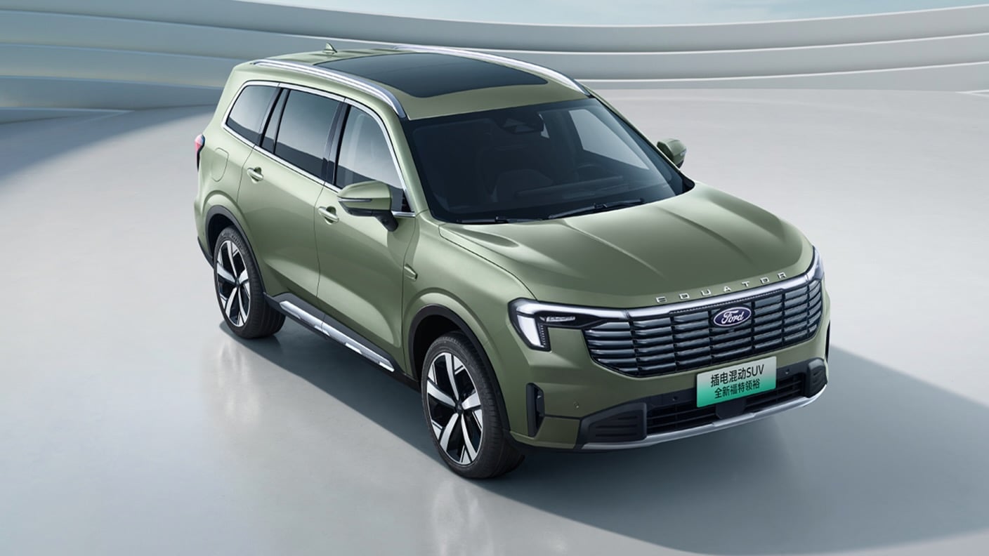 Three-quarter front view of a green Ford SUV in a bright studio, features roof rails and large alloy wheels.