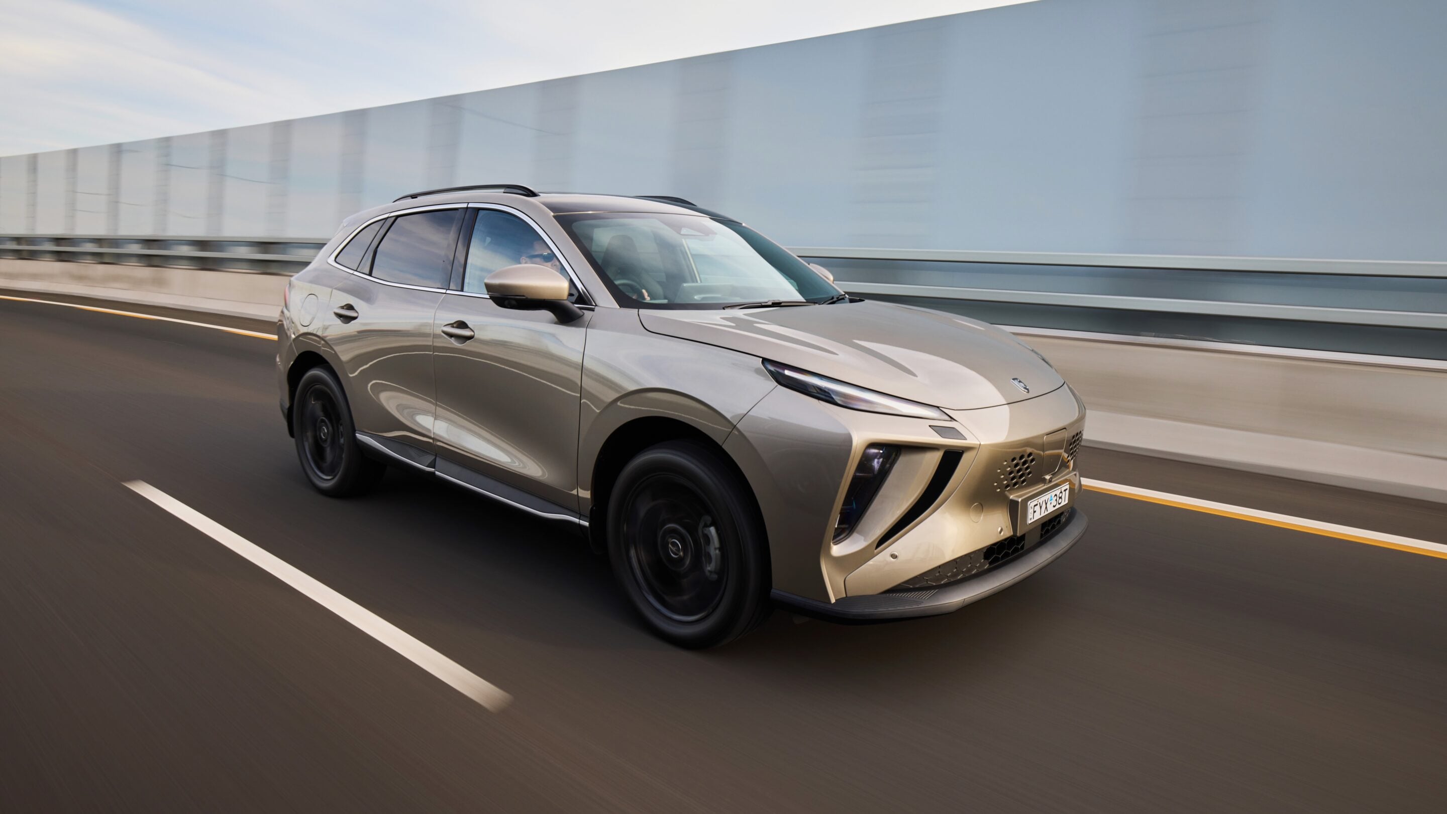 Side-front view of a silver SUV driving on a highway with blurred background, emphasizing speed and motion gravity of the scene.