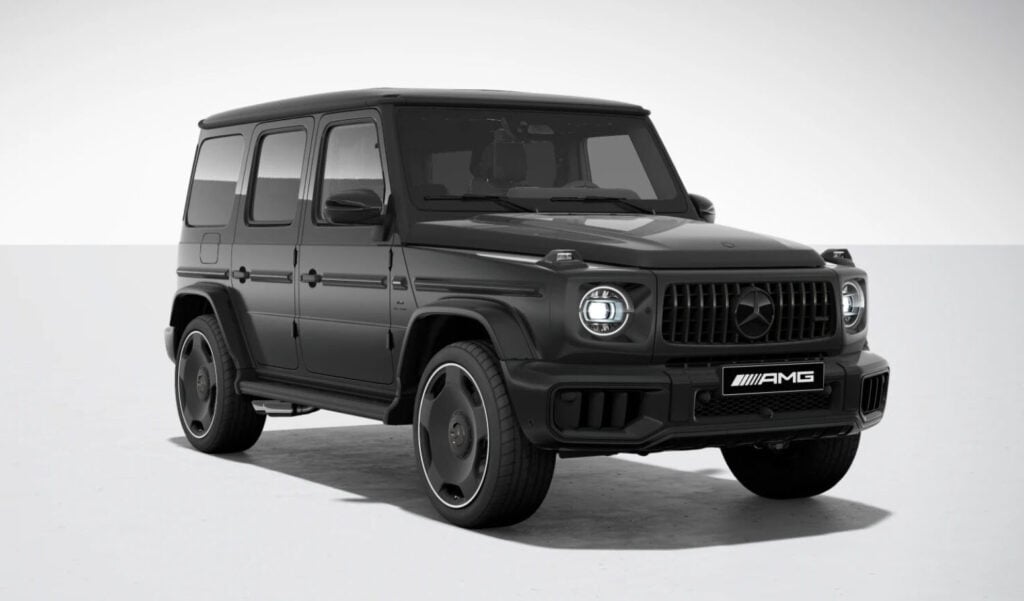 Front-left three-quarter view of a black Mercedes-Benz AMG G-Class SUV in a studio setting, showcasing its iconic grille and round headlights.