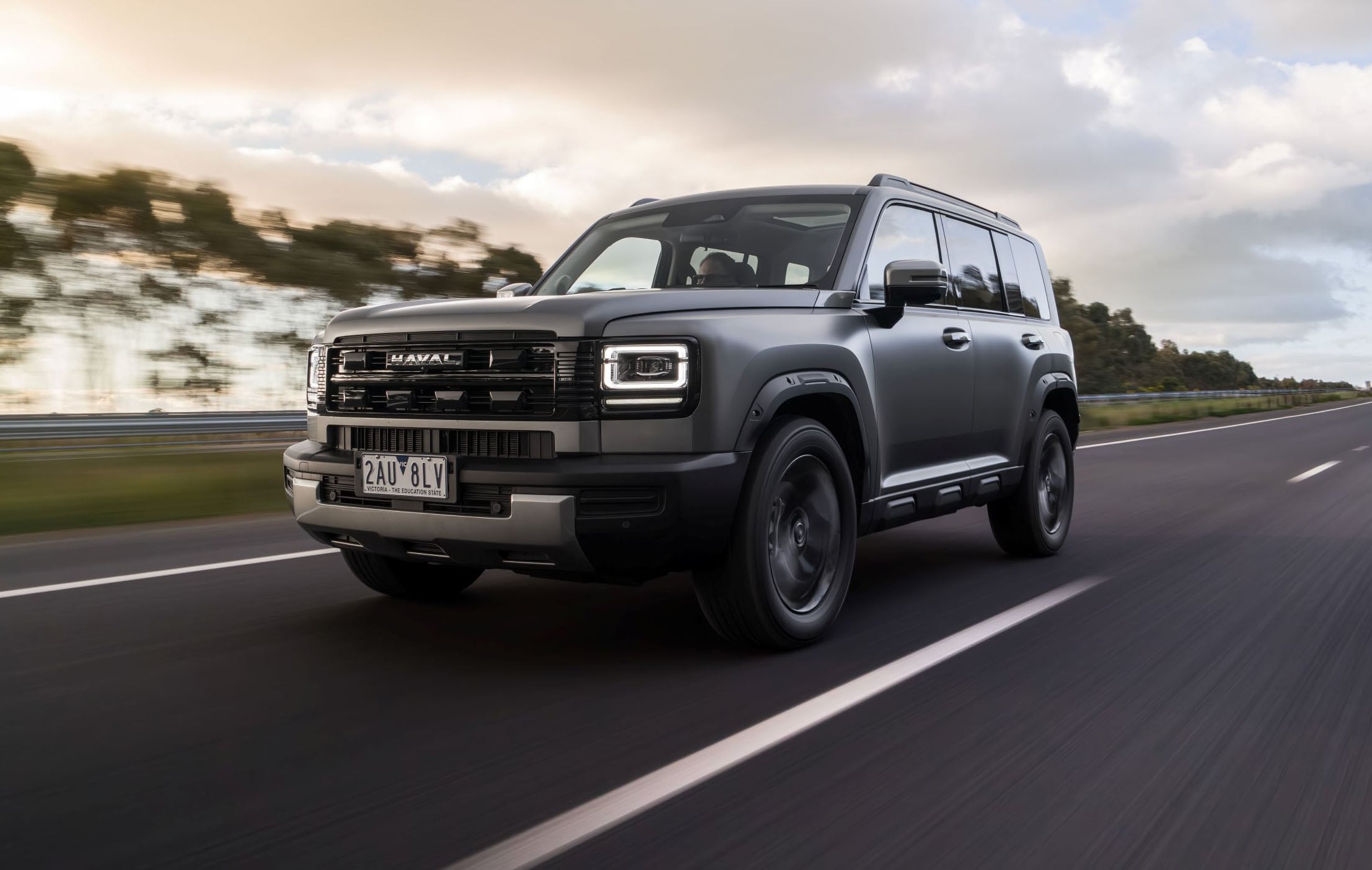 Gray Haval SUV driving at speed on a highway with blurred scenery in the background, front-left angle visible in motion