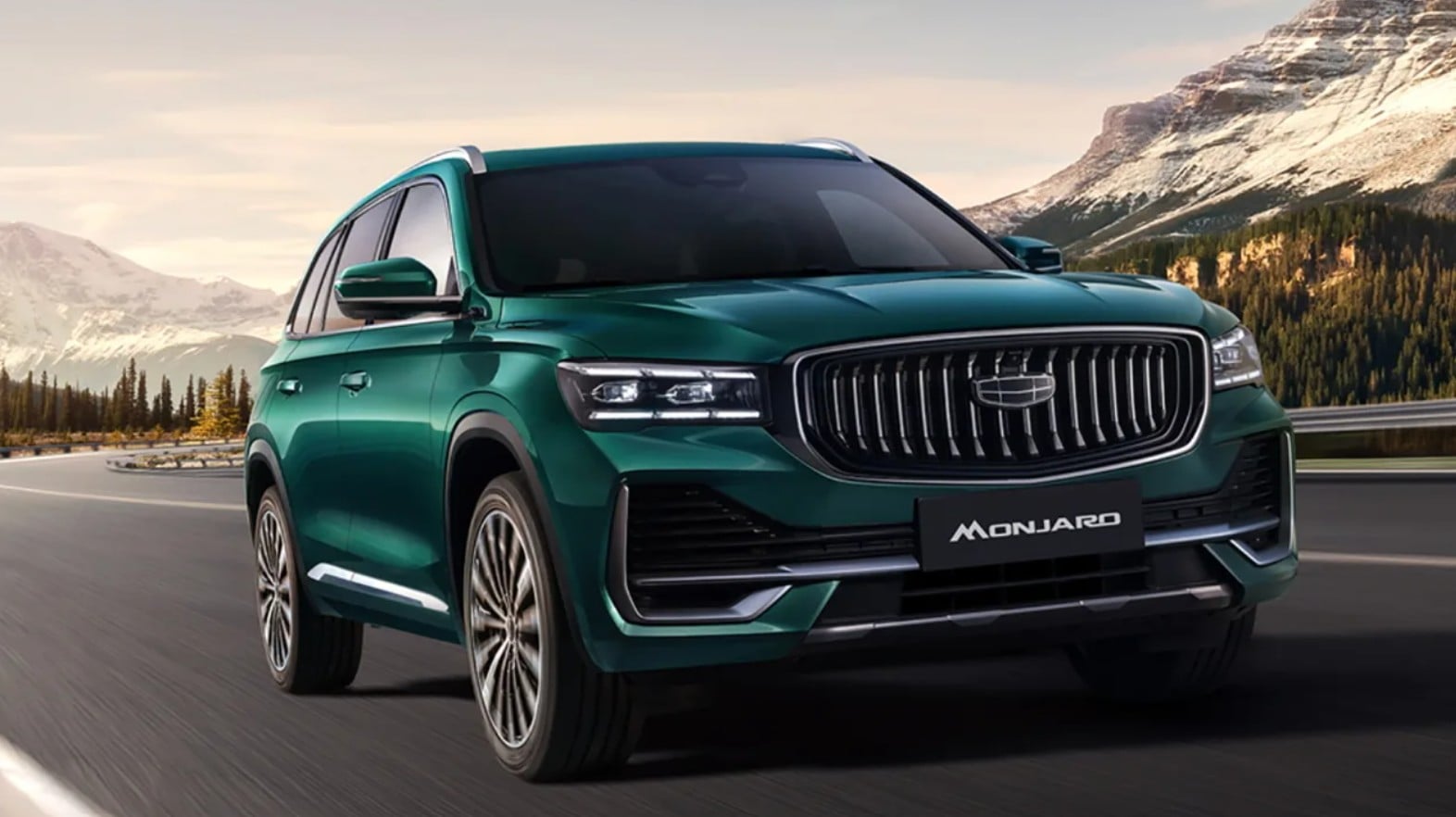 Teal SUV driving on a winding mountain road with snow-capped peaks in the background, front grille and chrome accents visible.