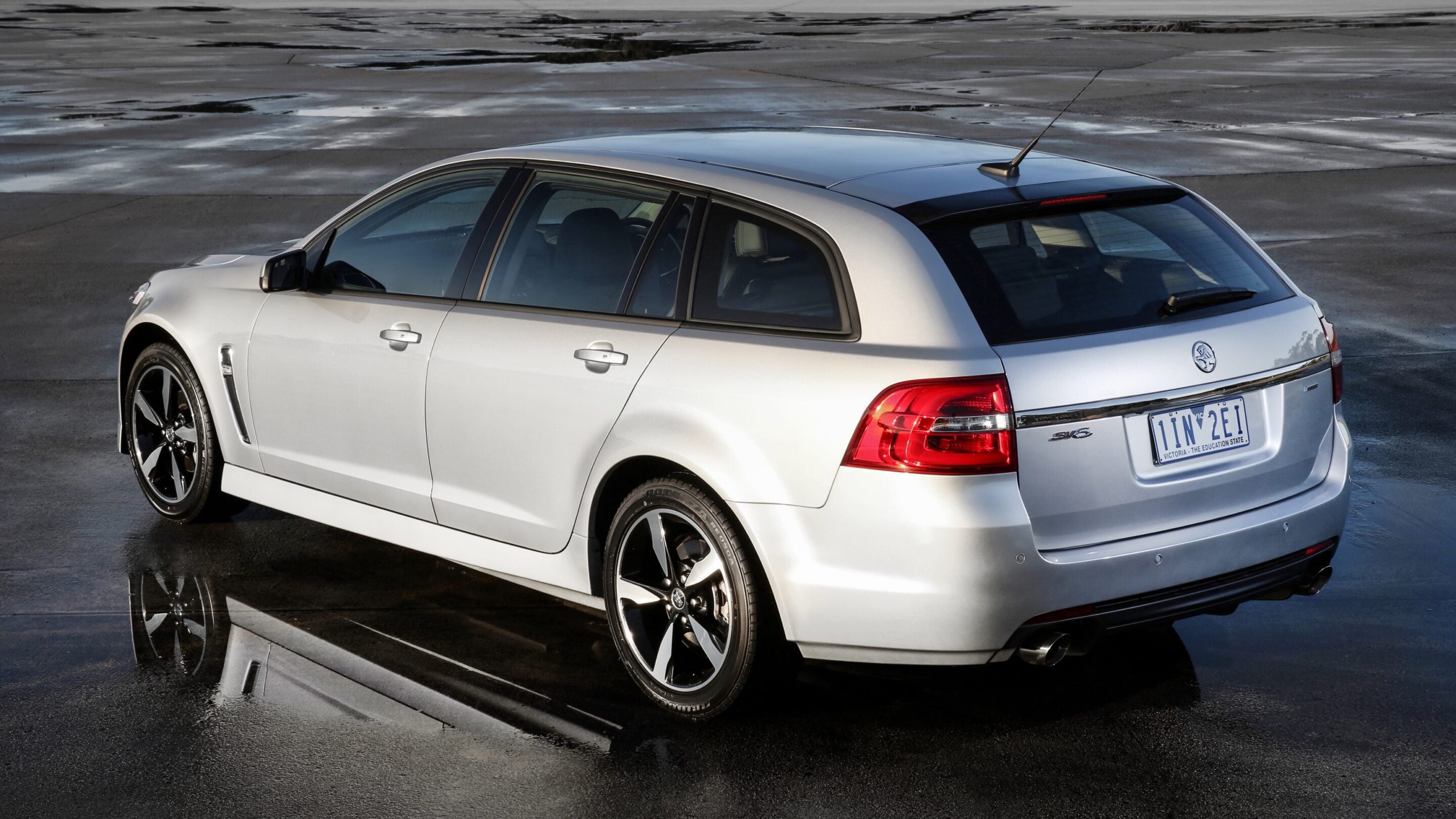 Rear three-quarter view of a silver station wagon on a wet surface, with visible tail lights and license plate.