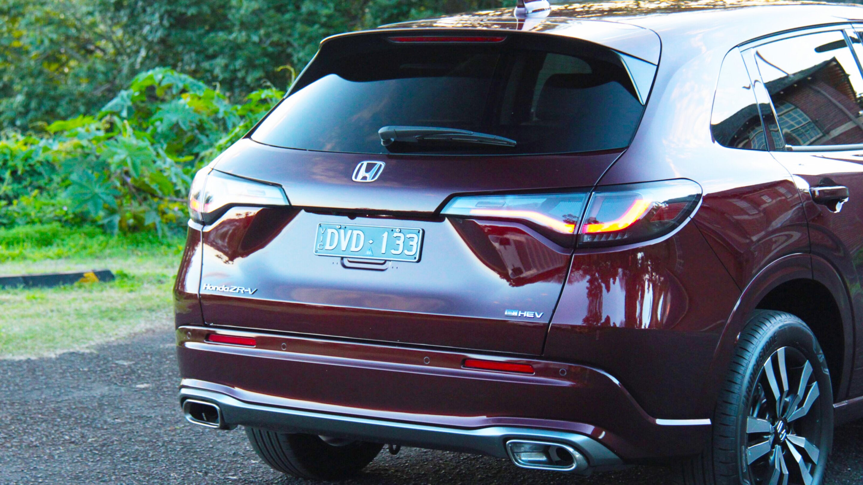 Rear view of a maroon Honda ZR-V SUV parked outdoors, showing the license plate DVD 133 and prominent taillights.