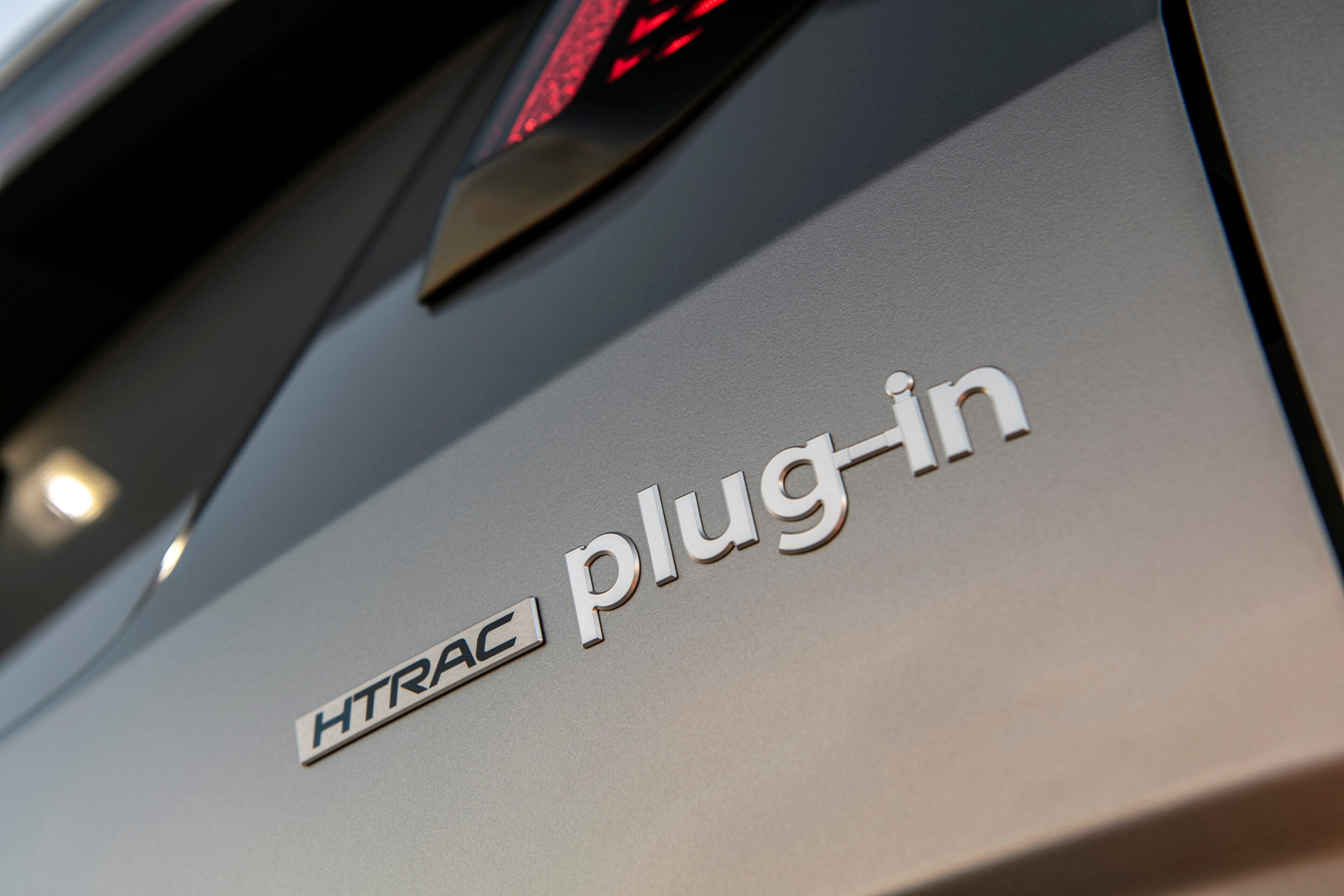 Close-up of a car badge reading 'HTRAC' on a gray vehicle surface.