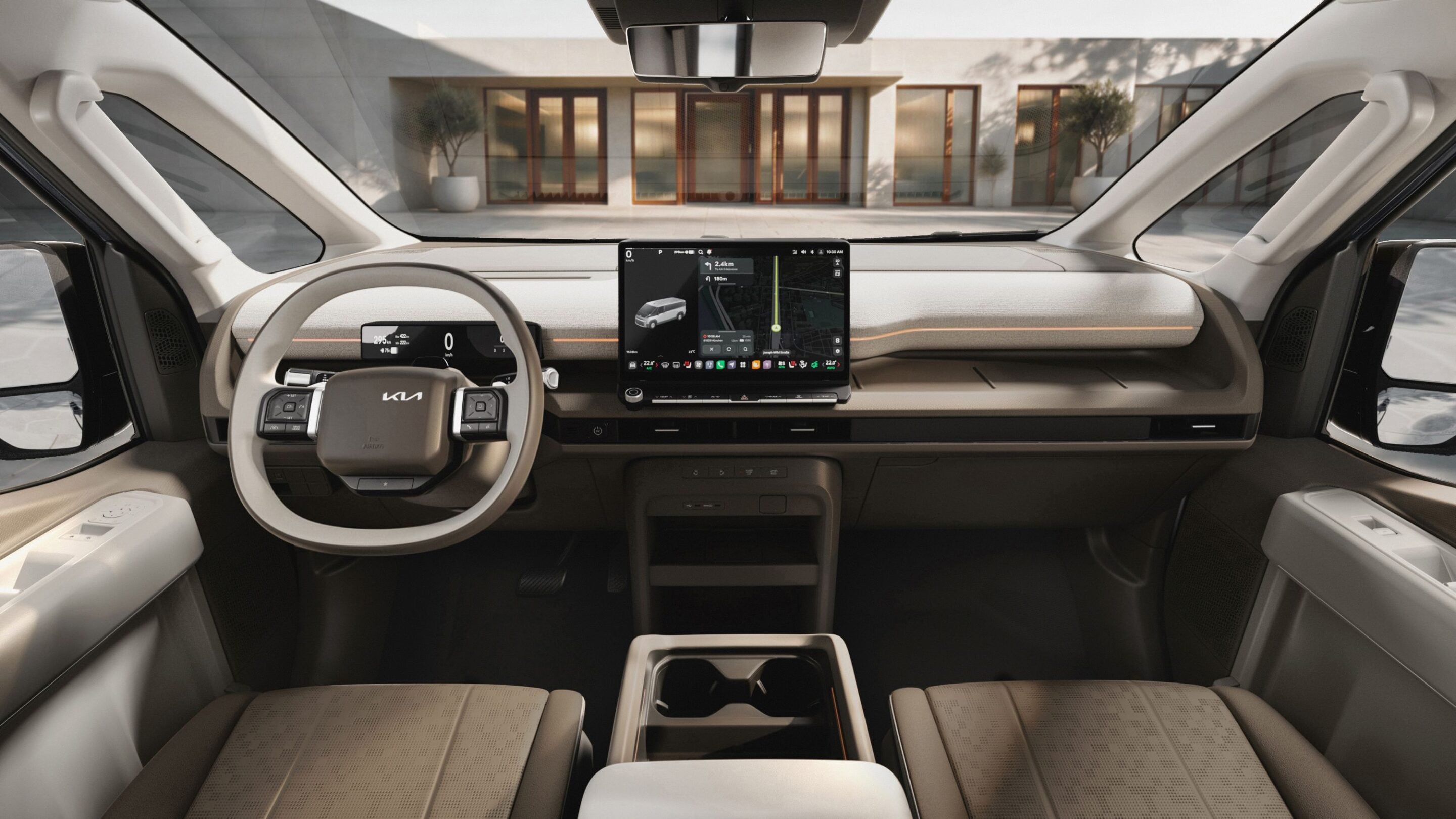 Driver’s-eye view of a modern car interior with a large central touchscreen showing a navigation map; building facade visible through the windshield.