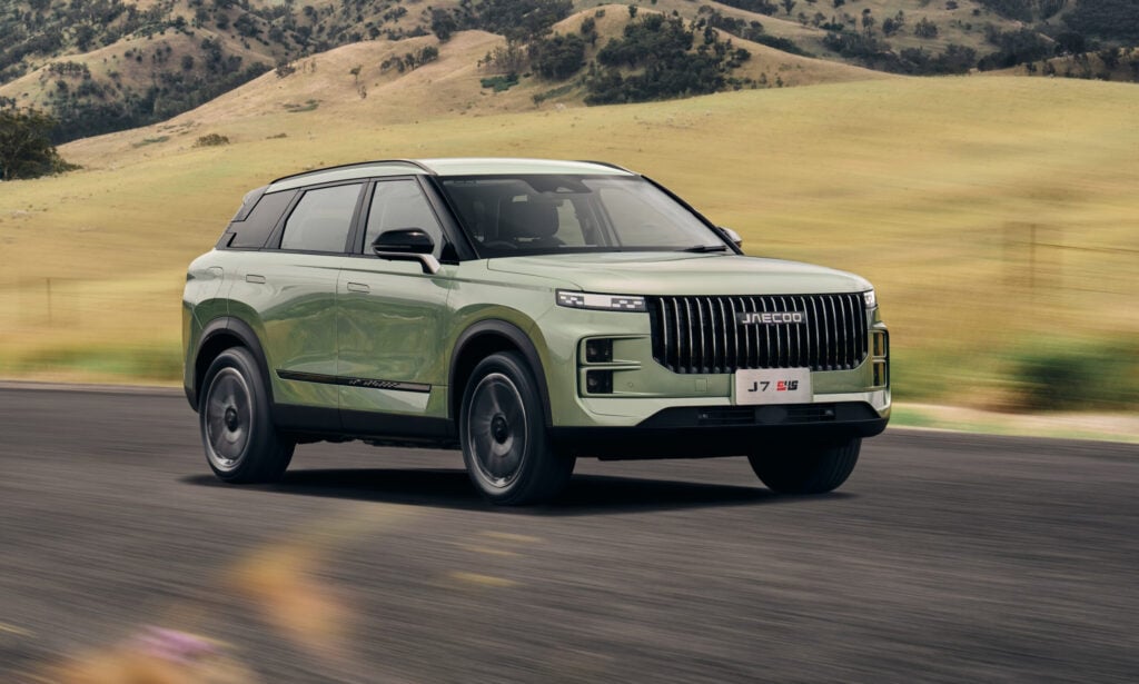 Green SUV in motion on a rural road with golden hills in the background.