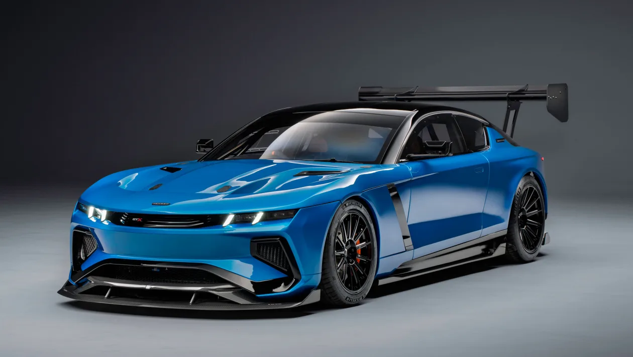 Blue high-performance sports car with aggressive front splitter and a large rear wing posed in a studio setting.